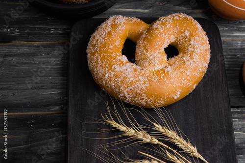 Pretzel in sugar on a wooden background in rustic style. Tasty dessert.