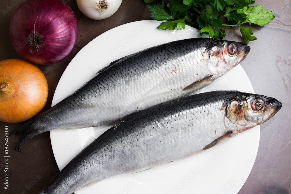 Herring on a marble table and ingredients. Tasty dish. Herring on a marble table and ingredients. Tasty dish.