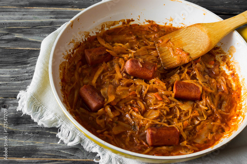 Bigus with sausages in a frying pan on a wooden background in rustic style photo