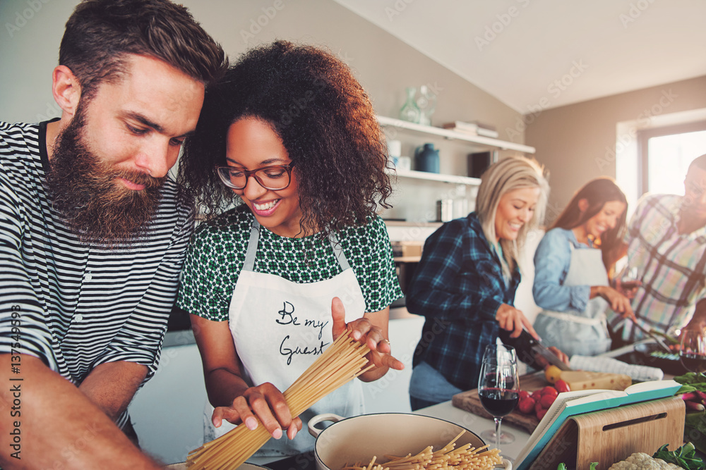 © Flamingo Images - Friends making pasta dinner in small kitchen © Flamingo Images - Friends making pasta dinner in small kitchen