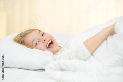 The cute girl yawn and lay on the bed