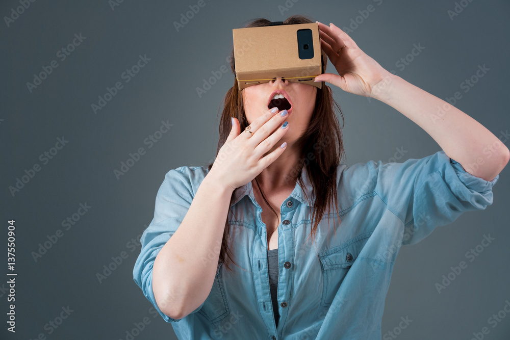 Woman using a new virtual reality headset on grey background Woman using a new virtual reality headset on grey background