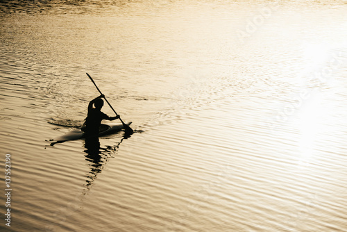 Woman canoer paddling in the sunrise.