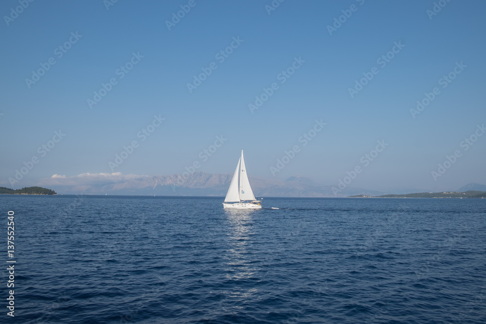 Big white yacht sailing on a clam blue sea with foggy mountains and green islands in the background. Vacation on a boat, sea, Greece.