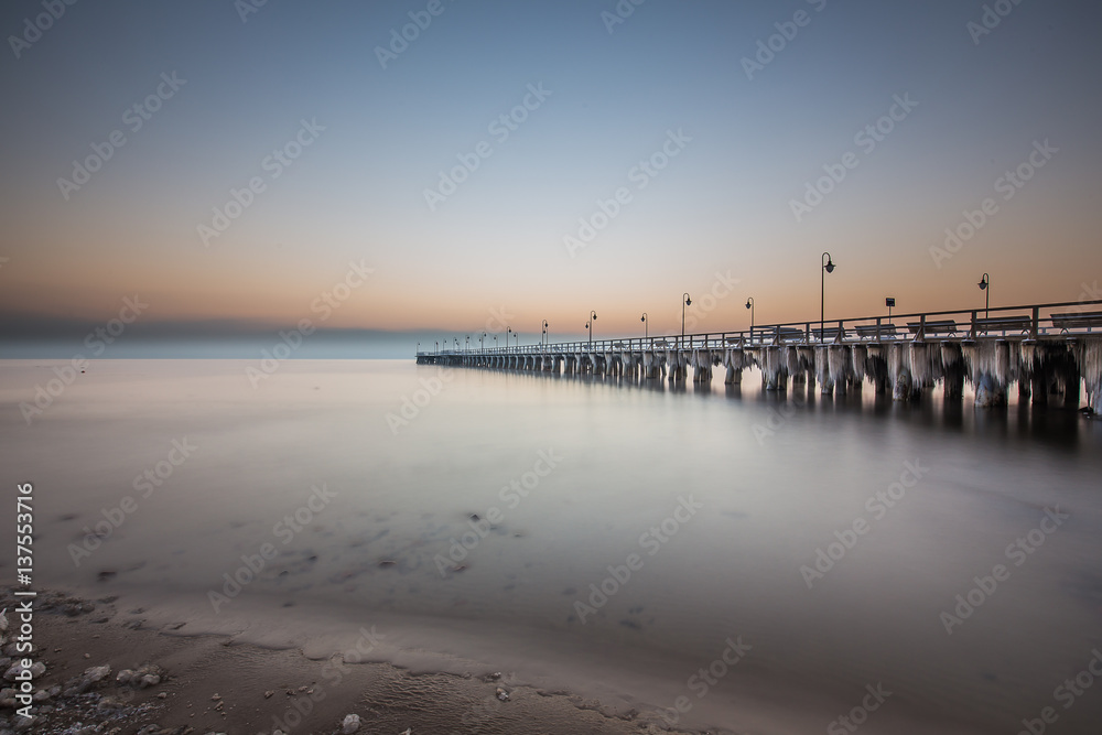 Winter scenery. Old pier in Gdynia Orlowo Poland with ice formations icicles. Frozen Sea Baltic seasonal specific.