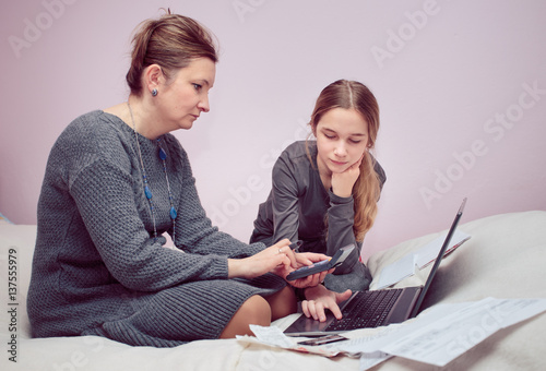 Woman and her daughter planning budget at home photo