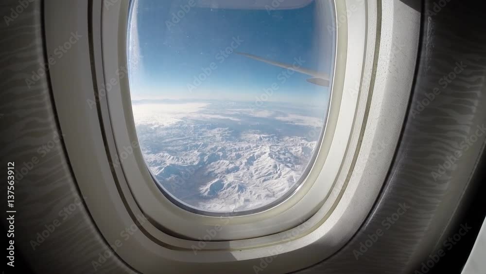 Traveling by air. Wonderful view of the sky, clouds and beautiful snow mountains from above, as seen through an airplane window-Dan Traveling by air. Wonderful view of the sky, clouds and beautiful snow mountains from above, as seen through an airplane window-Dan