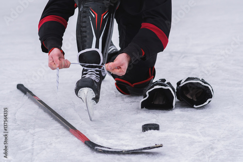 Photography hockey player sitting on the ice to tie shoelaces
