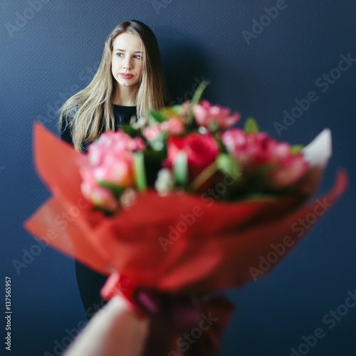 Cute girl getting bouquet of red tulips. Boyfriend giving tulips.