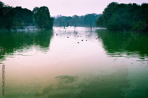 Beautiful sunset over the famous hauz khas lake in Delhi with trees and walkways bordering it. photo