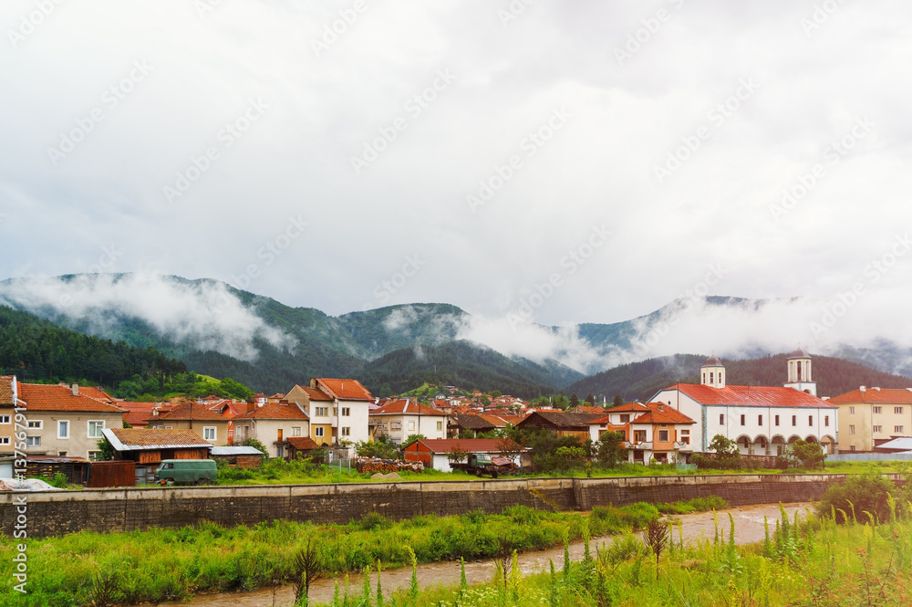 Mountain landscape. Country life. Old village in the mountains. Bright roofs after rain. Mountain River. Overcast sky