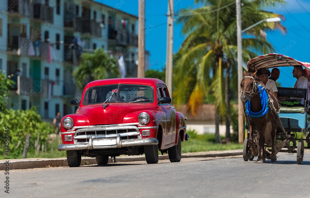 Roter Oldtimer parkt auf der Landstraße und wird von einer Pferdekutschen Taxi überholt in Santa Clara Kuba - Serie Kuba Reportage