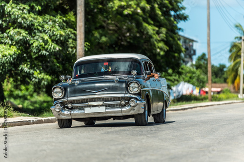 HDR - Schwarzer amerikanischer Oldtimer mit weissem Dach fährt auf der Landstraße im Vorort von Santa Clara Cuba - Serie Kuba Reportage