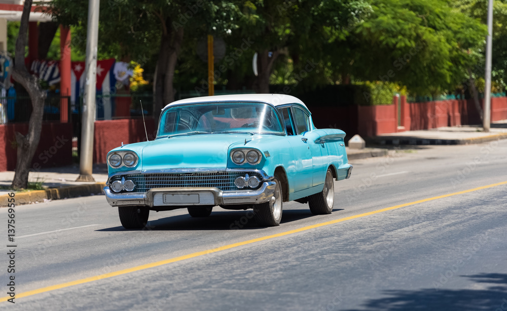 Blauer Oldtimer mit weißem Dach fährt auf der Straße durch Varadero Kuba - Serie Kuba Reportage