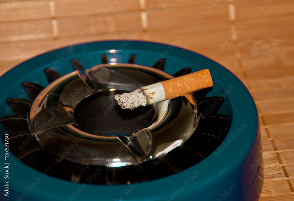 Gluttöter-Aschenbecher im Retro-Design mit brennender Zigarette Stock-Foto