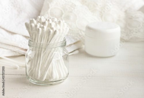  Cotton swabs in glass jar, white bathroom towel background. Personal care cleanliness product. 