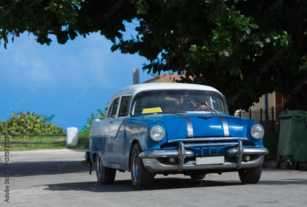 Blauer Oldtimer mit weissem Dach fährt durch die Vorstadt in Varadero Kuba - Serie Kuba Reportage