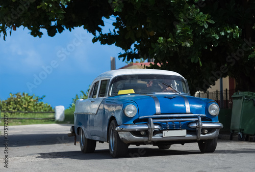 Blauer Oldtimer mit weissem Dach fährt durch die Vorstadt in Varadero Kuba - Serie Kuba Reportage
