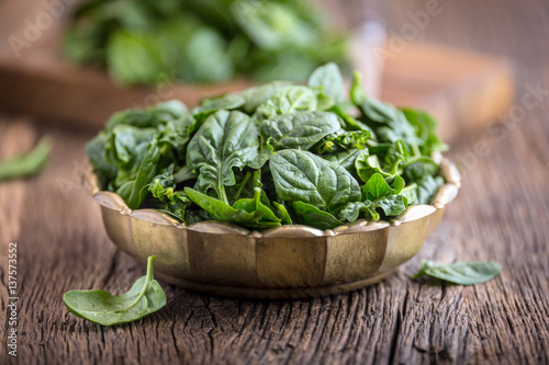 Spinach leaves.Fresh spinach leaves in retro bowl on oak wood board. Selective focus.
