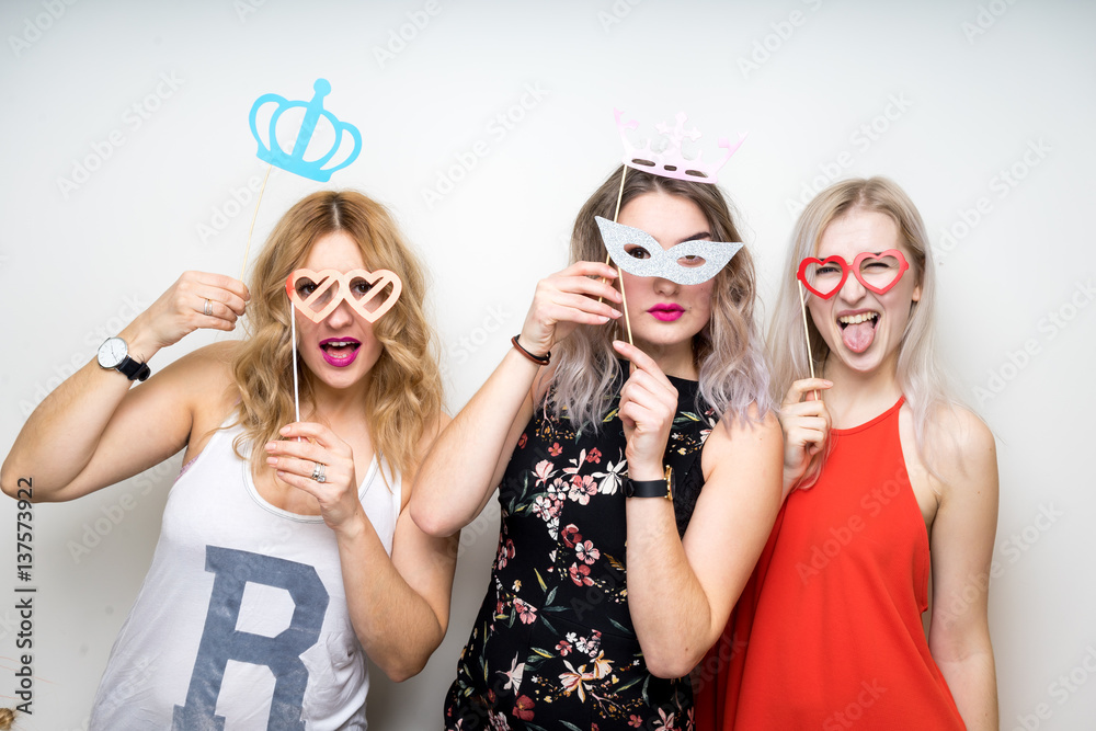three happy young ladies girls strike a pose on white background photo booth with party props
