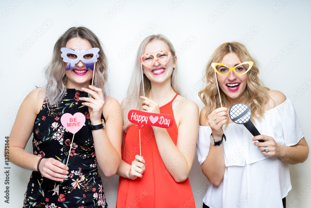three happy young ladies girls strike a pose on white background photo booth with party props