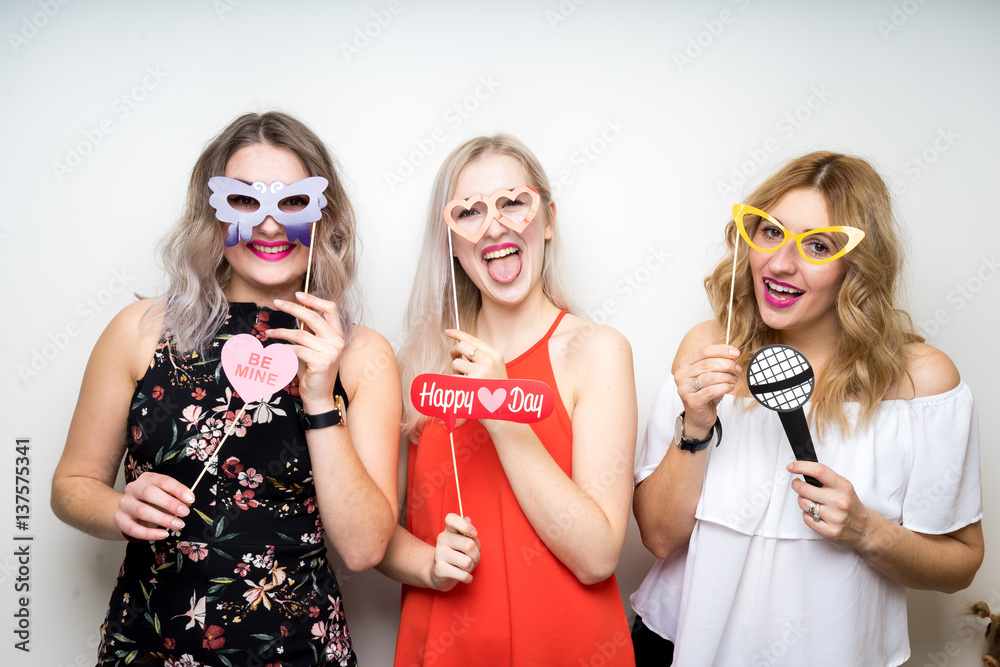 three happy young ladies girls strike a pose on white background photo booth with party props
