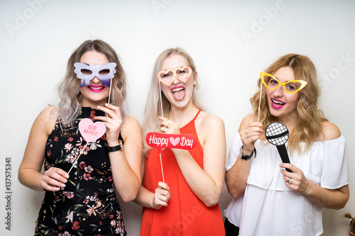 three happy young ladies girls strike a pose on white background photo booth with party props