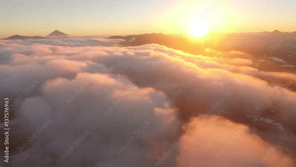 Aerial View. Sunset. The sun comes in the clouds behind the mountains Aerial View. Sunset. The sun comes in the clouds behind the mountains