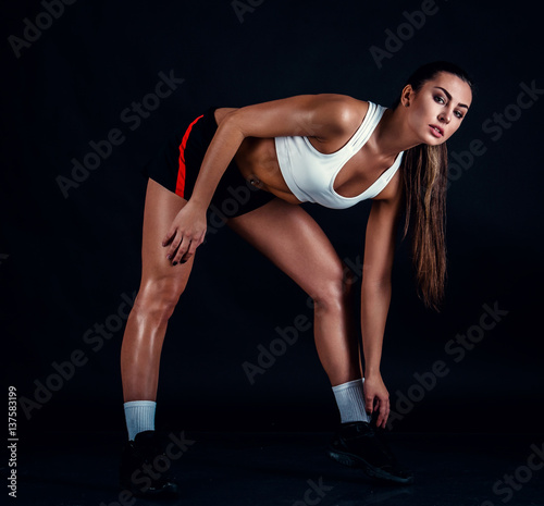 Athletic young woman doing a fitness workout against black background. Sporty woman in sportswear with perfect fitness body. © artyme