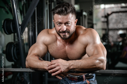 Fototapeta Naklejka Na Ścianę i Meble -  Brutal strong bodybuilder man pumping up muscles and train gym