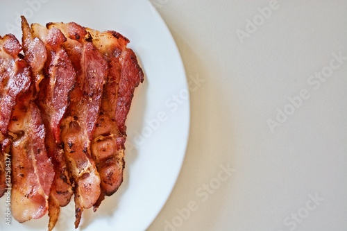 Fried bacon on the white plate on the white table 