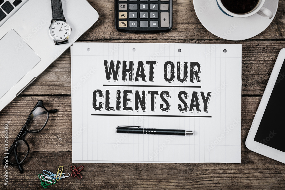 What Our Clients Say statement on notepad on office desk from above