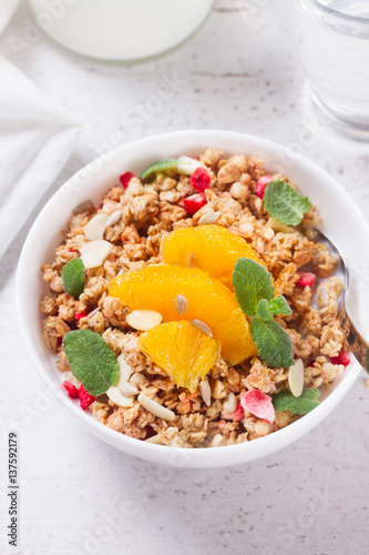 Healthy breakfast - plate of granola with orange slices, mint leaves and seeds close up