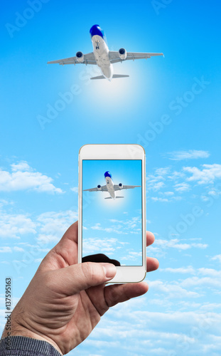 Man Hand holding using mobile phone and airplane on a blue background