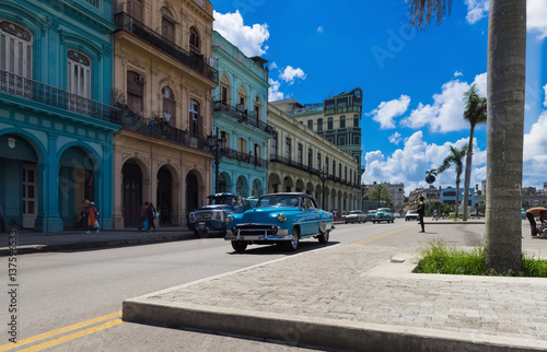 Amerikanischer blauer Oldtimer fährt an der historischen Häuserfront der Hauptstrasse vorbei in Havanna Kuba - Serie Kuba Reportage