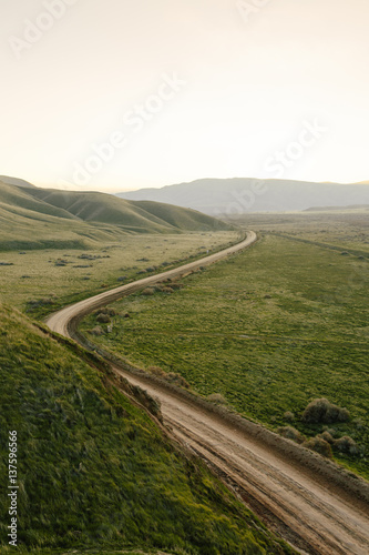 View of road passing through mountains in grassy landscape