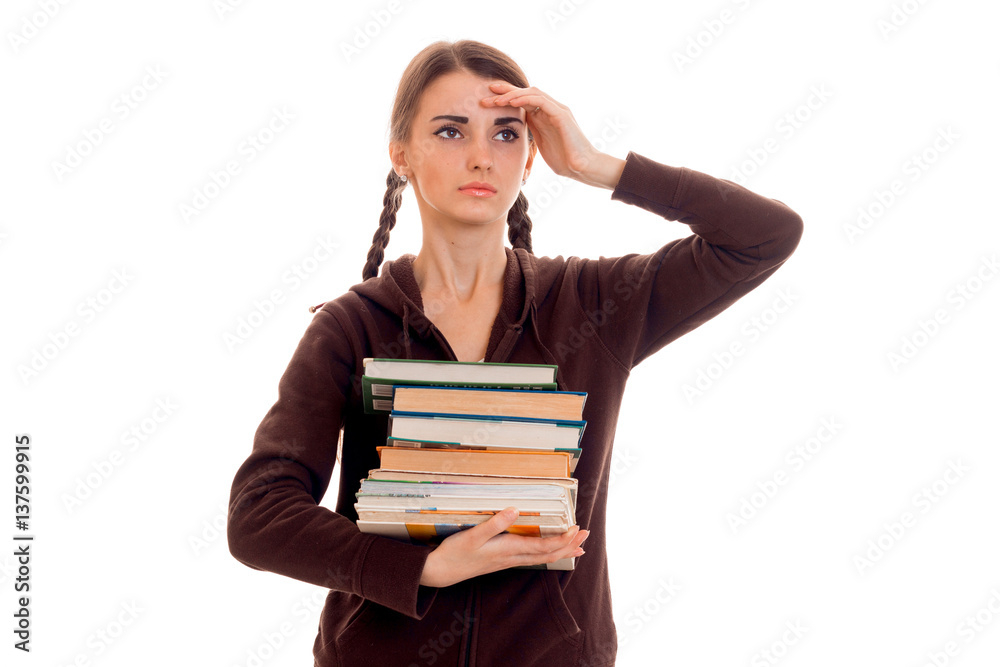 tired smart student girl in brown sport clothes with a lot of books in her hands posing isolated on white background tired smart student girl in brown sport clothes with a lot of books in her hands posing isolated on white background