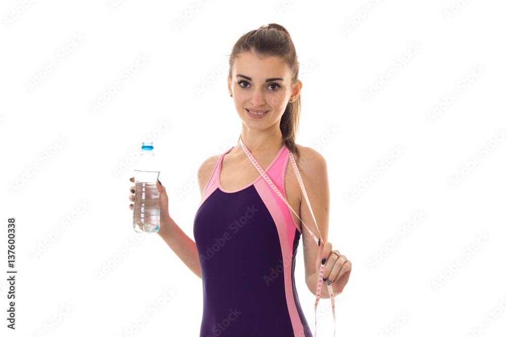 sexy young woman with bottle water and measure tape in magenta body swimsuit smiling on camera isolated on white background sexy young woman with bottle water and measure tape in magenta body swimsuit smiling on camera isolated on white background