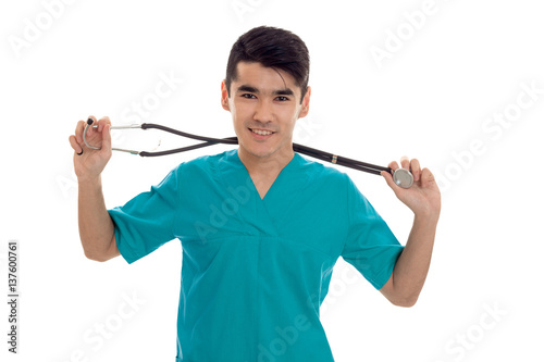 portrait of young handsome brunette man doctor in blue uniform with stethoscope looking and smiling on camera isolated on white background
