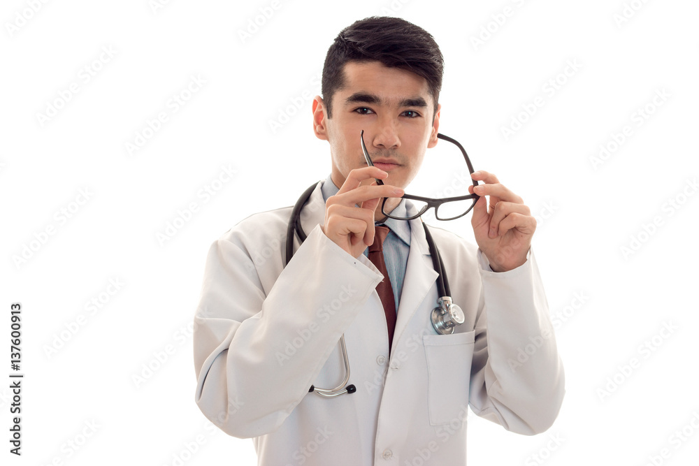 portrait of young handsome brunette man doctor in white uniform take off his glasses and posing on camera isolated on empty background portrait of young handsome brunette man doctor in white uniform take off his glasses and posing on camera isolated on empty background