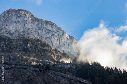Mountain cliff face with clouds and trees