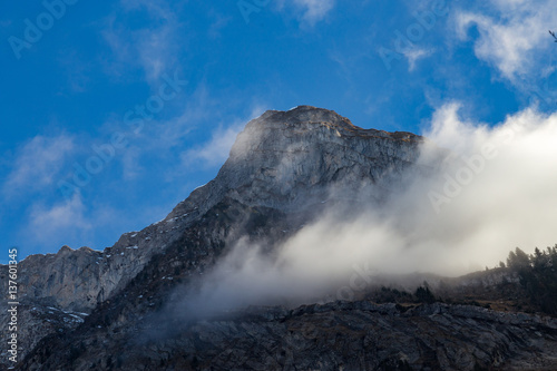 Mountain cliff face with clouds and trees