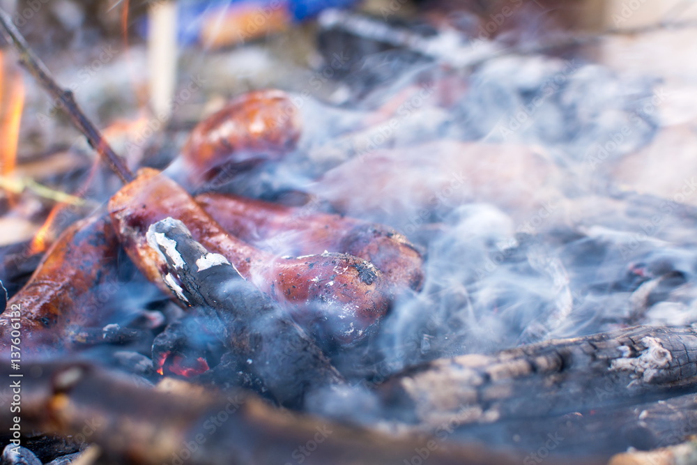 Sausages roasting on burning embers outdoors Sausages roasting on burning embers outdoors