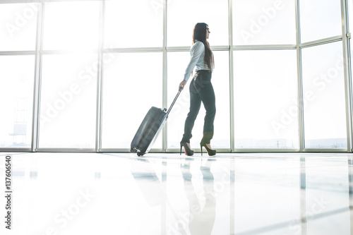 Business woman in airport running with baggage to registration on board
