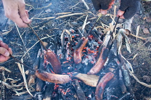 People roasting sausages on campfire