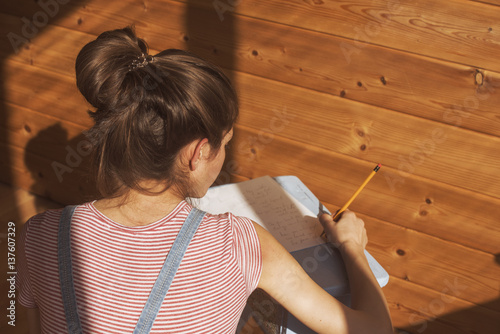 over shoulder view of a beautiful young woman, wrting a poem on a piece of paper  photo