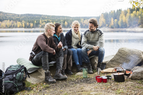 Friends Talking On Lakeshore During Camping