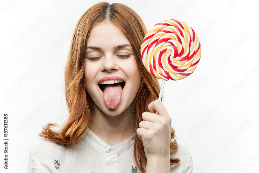 woman shows tongue, round lollipop near face