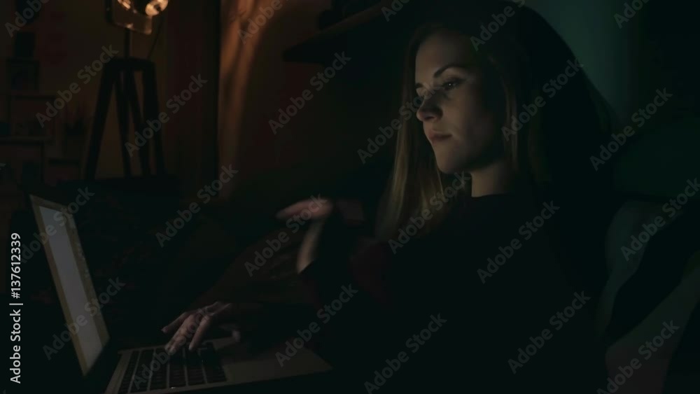 Young woman using laptop at night in dark room, indoor Young woman using laptop at night in dark room, indoor