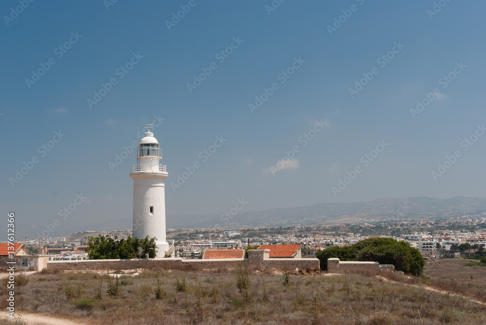White  lighthouse and road on deserted seashore near Paphos city, Cyprus
